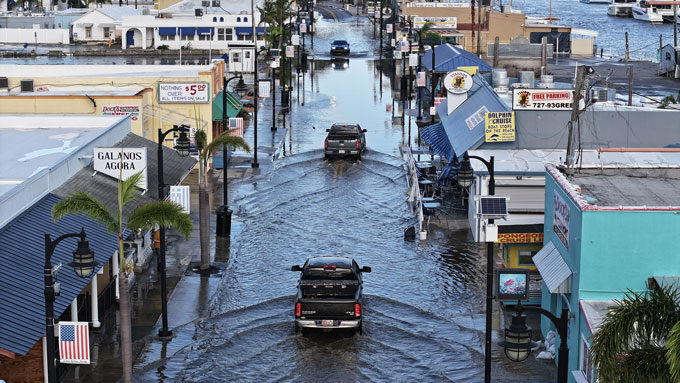 Trucks drive through a flooded road.